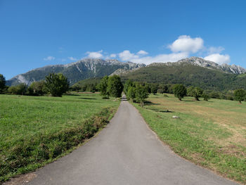 Road leading towards mountains against sky