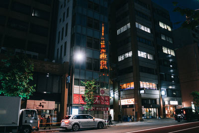 Illuminated street amidst buildings in city at night