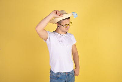 Midsection of man wearing hat standing against yellow background