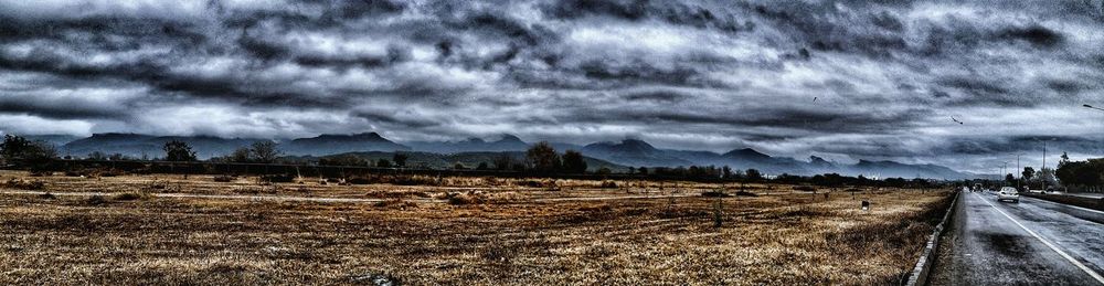 Road by field against storm clouds