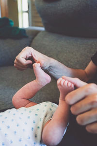 Cropped hand of father holding baby feet at home