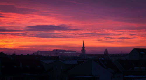 Silhouette of buildings against cloudy sky during sunset