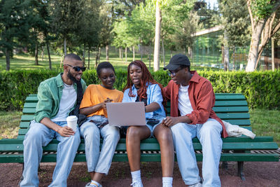 Friends using laptop at park