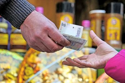 Cropped hand of man giving paper currency to woman at market