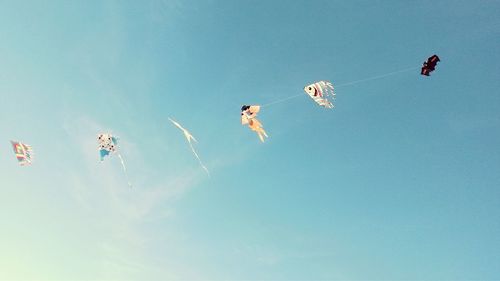 Low angle view of kites flying against sky