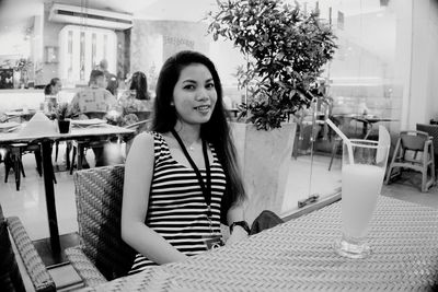 Portrait of young woman sitting on table at cafe