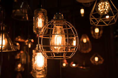 Close-up of illuminated light bulb hanging at night