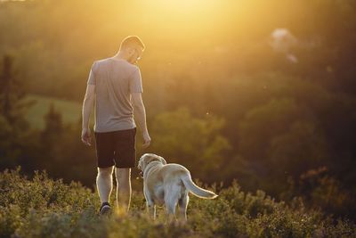 Rear view of man with dog on field