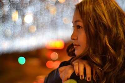 Close-up portrait of young woman looking away at night