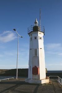 Low angle view of lighthouse by building against sky