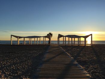 Scenic view of beach against clear sky during sunset