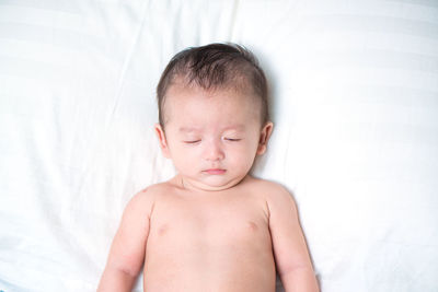 Close-up of shirtless baby on bed