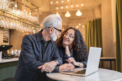 Mature couple using laptop in cafe