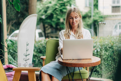 Young woman using laptop while sitting on table