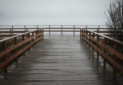 Wooden footbridge on pier against sky