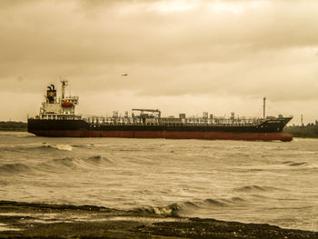 Boats in sea against cloudy sky