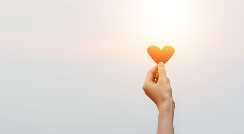 Cropped hand holding heart shape against white background