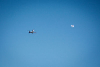 Low angle view of airplane against clear blue sky