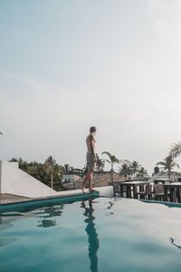 Man jumping in swimming pool against sky