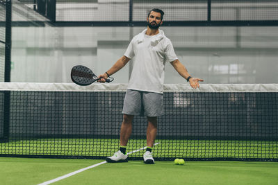 Man playing padel tennis, racket in hand wipes the sweat. young sporty boy at the end of the match. 