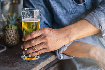 Midsection of man drinking glass on table