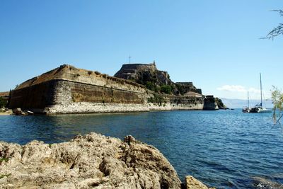 View of built structure by sea against clear sky