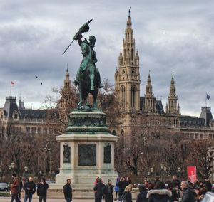 Statue in city against cloudy sky