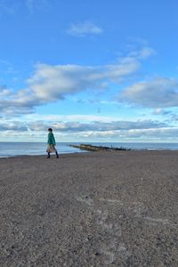 Full length of woman on beach against blue sky