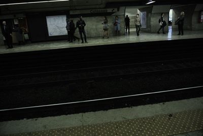 People walking on railroad station platform at night