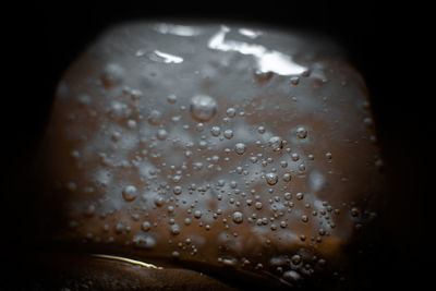 Close-up of wet glass against black background