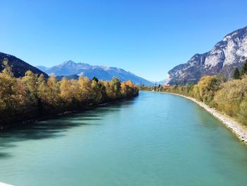 Scenic view of lake and mountains against clear blue sky