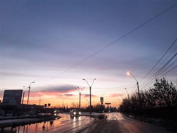 Cars on road against sky at sunset