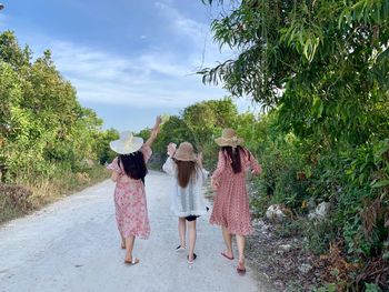 Rear view of women walking along plants