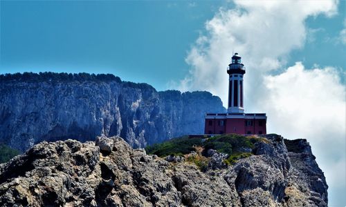 Lighthouse on cliff against blue sky