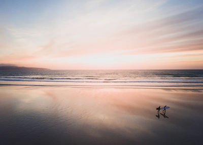 People walking on shore at beach against sky