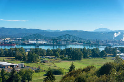 Scenic view of river by mountains against clear blue sky