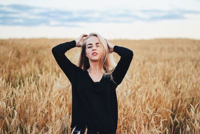 Portrait of beautiful woman standing at wheat farm