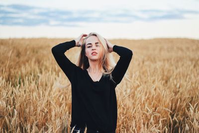 Portrait of beautiful woman standing on field against sky