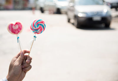 Cropped hand having lollipops on road