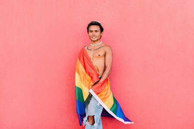 Gay man with rainbow flag against pink background