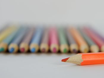 Close-up of colored pencils on table against white background