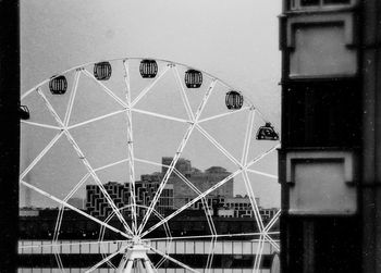 Low angle view of ferris wheel against building in city