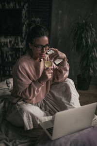 Midsection of woman drinking water from while sitting at home