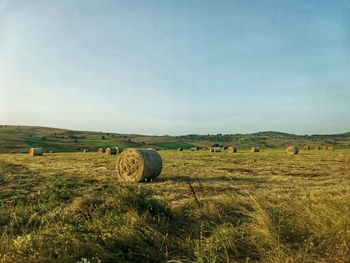 Hay bales on field against sky