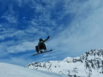 Low angle view of man jumping against sky