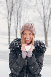 Portrait of smiling young woman standing outdoors during winter