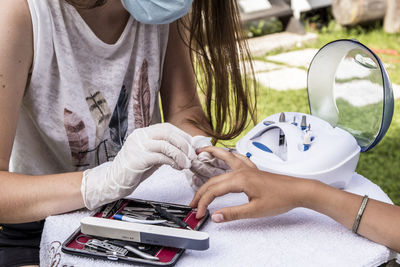 Outdoor manicure between young girls in the time of coronavirus using  face mask and gloves.