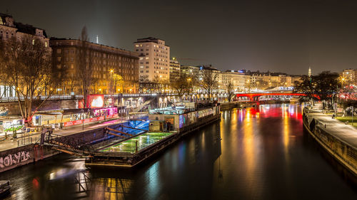 Illuminated bridge over river in city at night