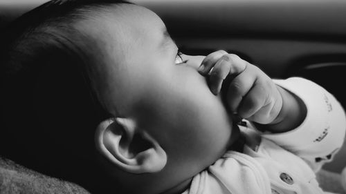 Close-up of cute baby girl lying in car