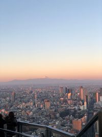 Aerial view of city buildings against clear sky during sunset